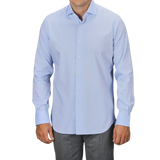 A person wearing an Alessandro Gherardi Sky Blue Cotton Twill Single Cuff Shirt and gray pants. The background is plain and not visible.