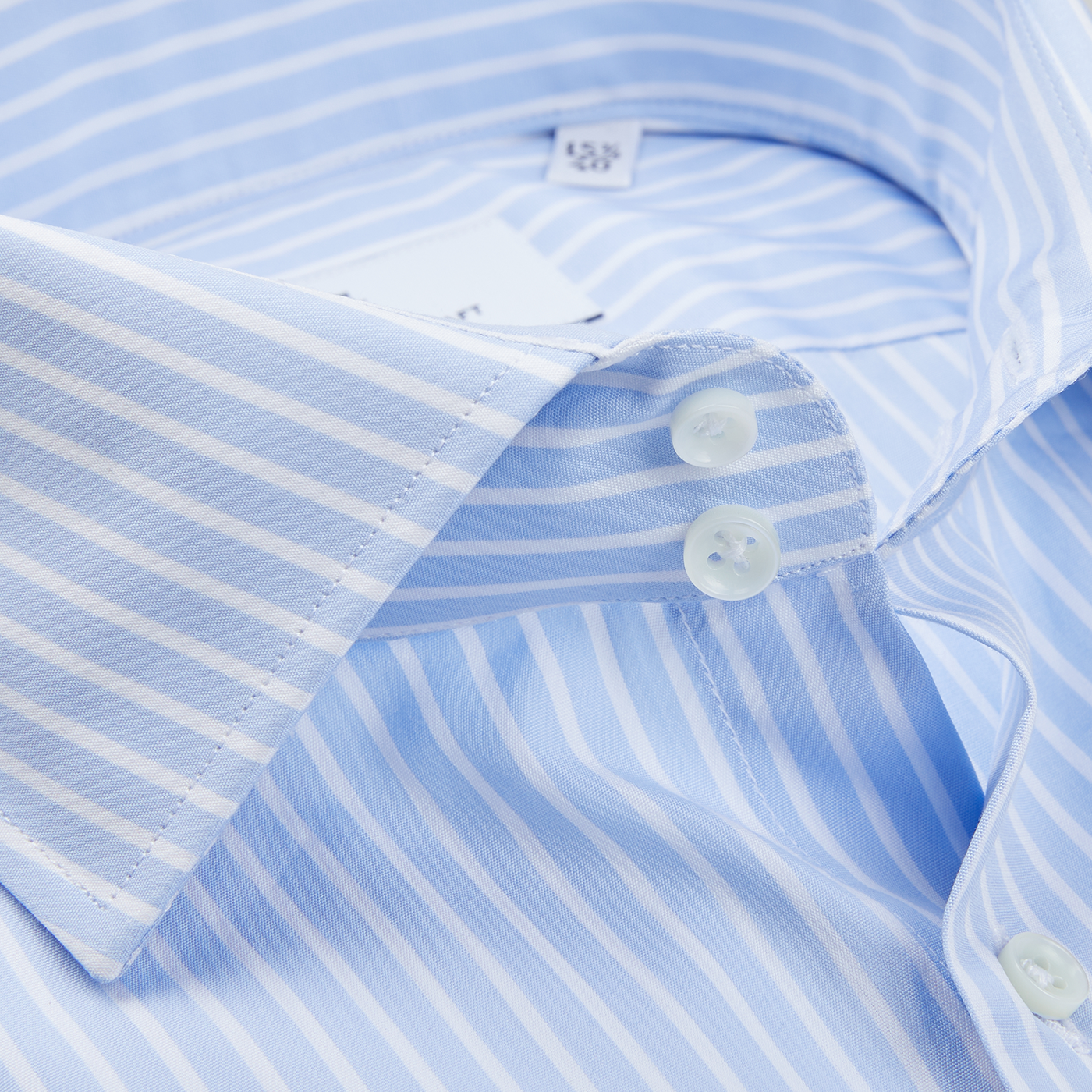 A close up of an Alexander Kraft Monte Carlo blue and white striped Egyptian cotton dress shirt, featuring mother-of-pearl buttons.