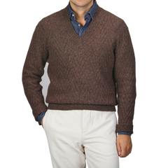 A person wearing an Altea Brown Wool Chevron Knit V-Neck over a blue denim shirt, paired with light beige pants.