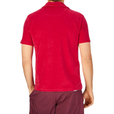 Rear view of a person wearing an Altea Coral Red Cotton Towelling Capri Collar Polo Shirt and maroon shorts against a grey background.