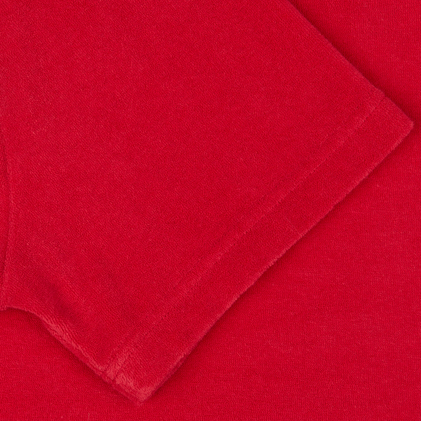 A coral red organic cotton towelling fabric or textile with a smooth texture laid out flat.