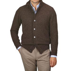 A person wearing the Altea Dark Brown Shetland Wool Button Cardigan over a blue dress shirt with beige pants, standing against a plain gray background.