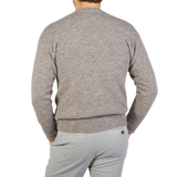 The back view of a man wearing an Altea Grey Melange Wool Alpaca Crewneck Sweater and gray pants.