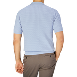 A man standing with his back to the camera, wearing a Altea Light Blue Cotton Capri Collar Polo shirt and beige trousers.