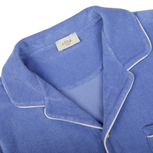 Close-up of a Light Blue Cotton Towelling Capri Collar Shirt made from organic cotton with white piping and a tag with handwriting on the collar by Altea.
