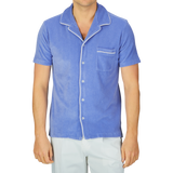 Man wearing an Altea light blue cotton towelling capri collar shirt with white piping and white pants.