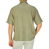 A man viewed from behind wearing an Altea Moss Green Linen Blend Camp Collar shirt and light-colored pants.