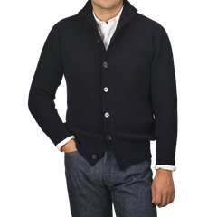 A person wearing an Altea Navy Blue Shetland Wool Button Cardigan over a white shirt, with one hand in their pocket, stands against a plain gray background.