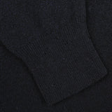 A close-up of a black knitted fabric with a ribbed cuff, part of the Navy Blue Wool Fleece 1/4 Zip Sweater by Altea.