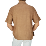 Man wearing an Altea Tobacco Brown Linen Blend Camp Collar Shirt with mother-of-pearl buttons and white pants, viewed from the back.