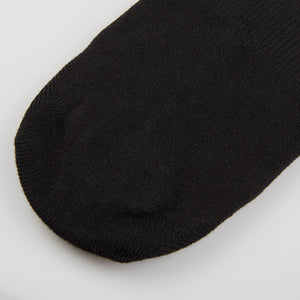 A close up of a Amanda Christensen Black Cotton Invisible Sock on a white surface.