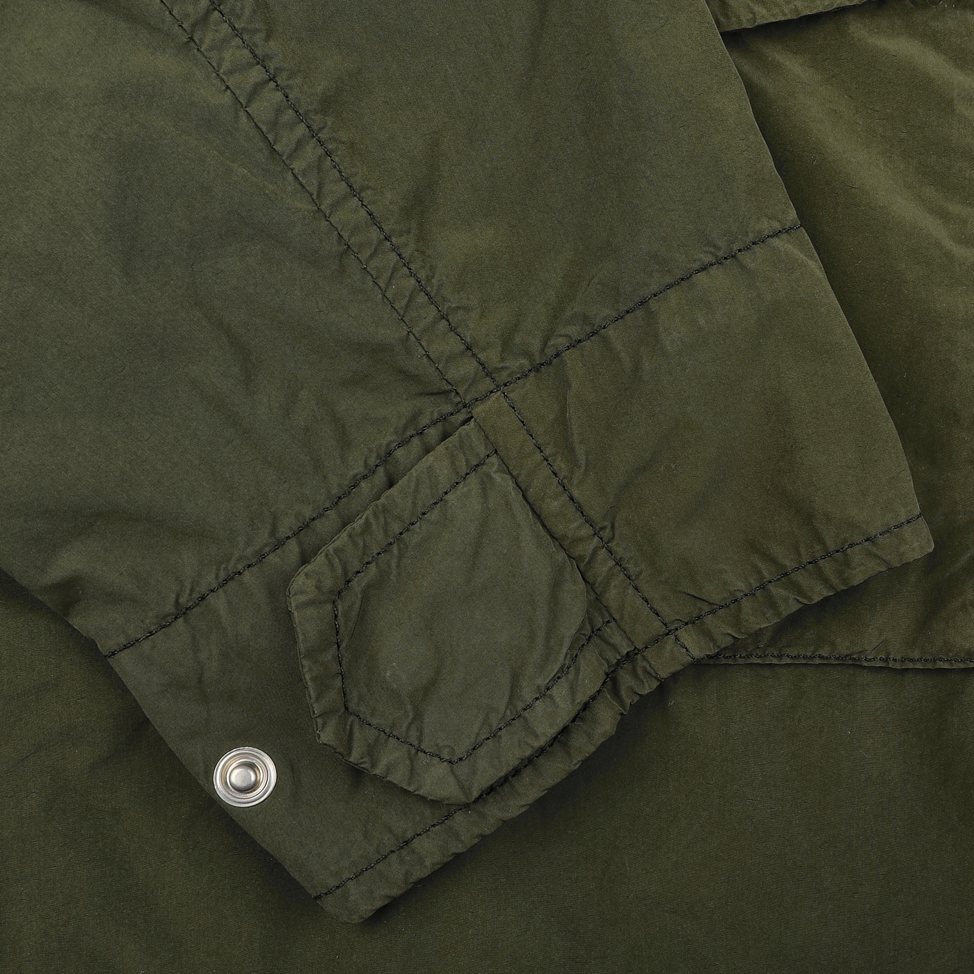 A close-up of the Aspesi Army Green Luxury Nylon Field Jacket reveals its classic M65 military-inspired design, featuring a pocket flap with intricate stitching and a durable metal snap button.