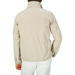 The back view of a man wearing an Aspesi Beige Cotton Canvas Windbreaker Stringa Jacket.