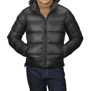 A person wearing an Aspesi Black Nylon Ripstop Down Padded Budd Jacket over a brown turtleneck sweater and blue jeans, with hands in pockets.