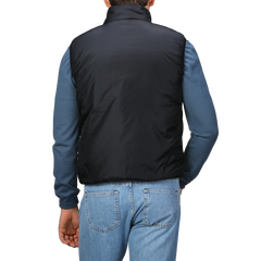 A person is shown from the back wearing an Aspesi Black Nylon Taffeta Thermore Jil Gilet over a blue long-sleeve shirt and denim jeans.