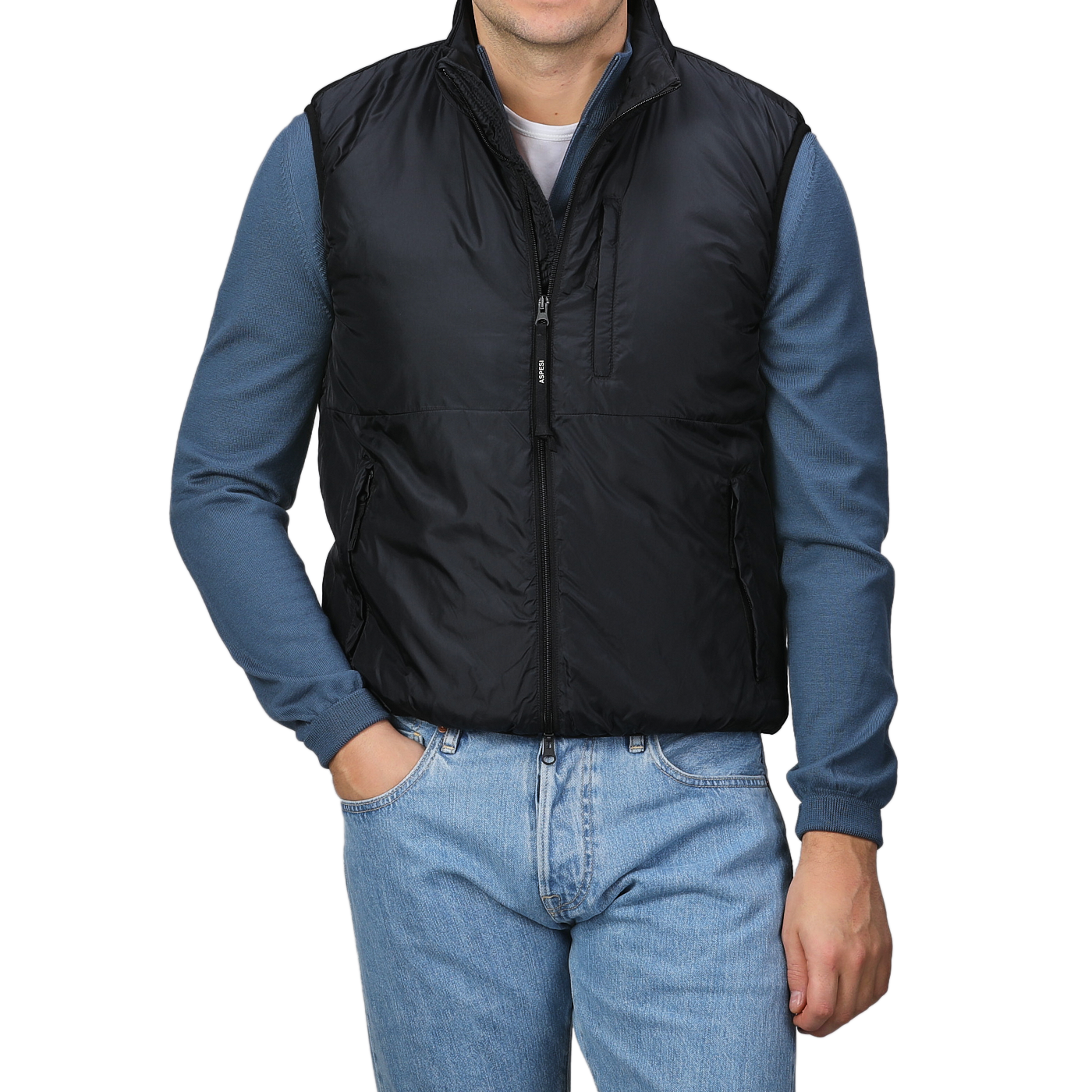 A man stands with his hands in his pockets, wearing the Aspesi Black Nylon Taffetta Thermore Jil Gilet over a blue long-sleeve shirt and blue jeans, set against a plain background.