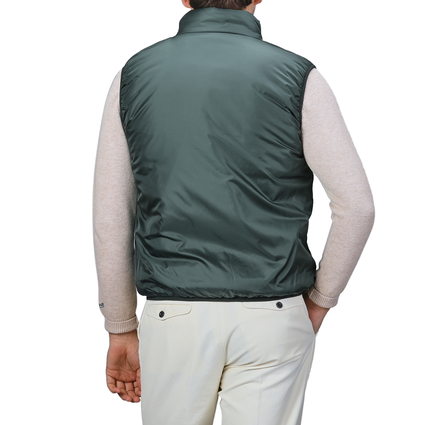 A person wearing the Aspesi Bottle Green Nylon Taffeta Thermore Jil Gilet, a light beige long-sleeve sweater, and light-colored pants, shown from the back.