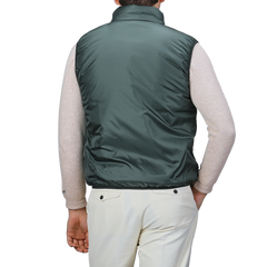 A person wearing the Aspesi Bottle Green Nylon Taffeta Thermore Jil Gilet, a light beige long-sleeve sweater, and light-colored pants, shown from the back.