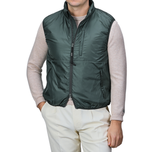 An individual sporting an Aspesi Bottle Green Nylon Taffeta Thermore Jil Gilet over a beige sweater and light trousers stands with one hand in their pocket.