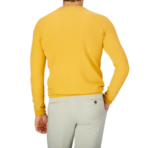 The back view of a man wearing a Aspesi Bright Yellow Cotton Piquet Crew Neck Sweater and khaki pants.