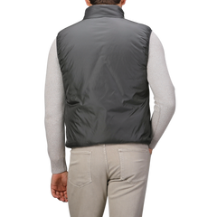 A person seen from the back is dressed in an Aspesi Charcoal Grey Nylon Taffetta Thermore Jil Gilet over a light gray sweater, paired with beige pants.