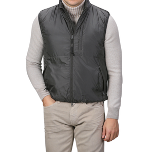 A person wearing the Aspesi Charcoal Grey Nylon Taffetta Thermore Jil Gilet over a gray sweater and light gray pants, with hands in pockets.