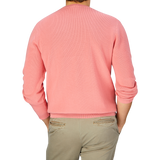 The back view of a man wearing a Coral Pink Knitted Cotton Sweater by Aspesi and khaki pants.