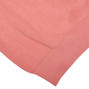 A close up of a coral pink, cotton Aspesi crew neck sweater on a white background.