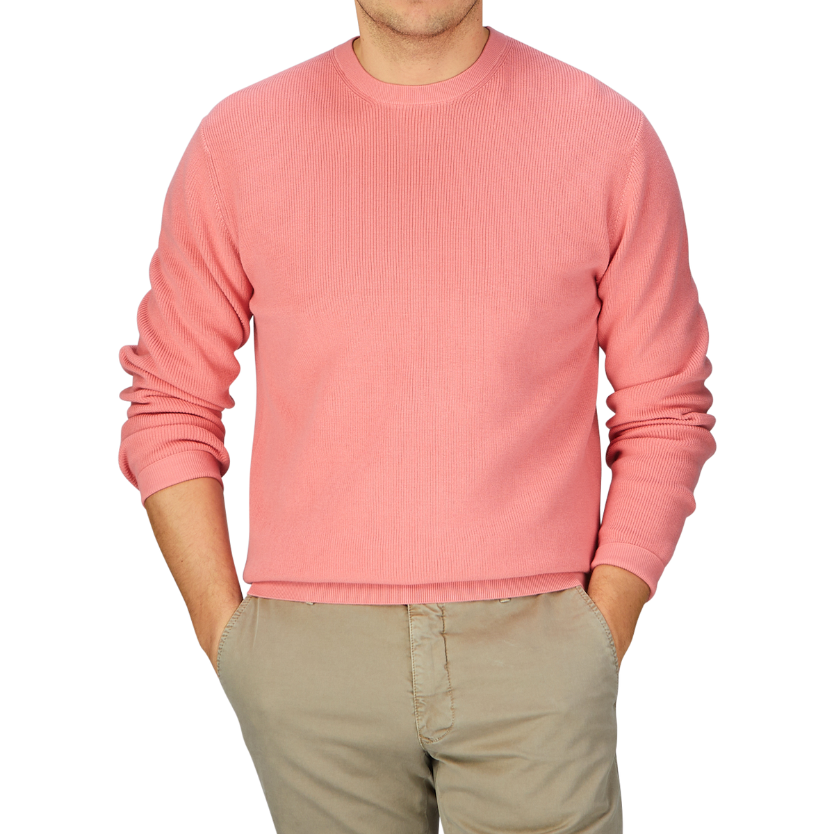 A man wearing a coral pink knitted cotton sweater from Aspesi and khaki pants.
