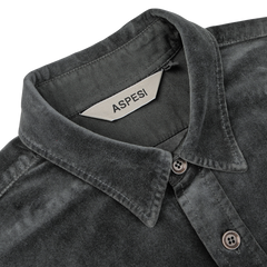 Close-up of the Dark Grey Cotton Velvet Overshirt with a tag inside the collar labeled "Aspesi." This Italian outerwear piece, made from pure cotton velvet, features a button-down collar and visible stitching details.