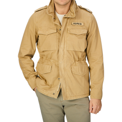 A man wearing a tan windproof Aspesi field jacket and khaki beige cotton mini pants.