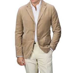 A person wearing an Aspesi Light Beige Cotton Velvet Isaac Blazer over a white shirt with beige pants.