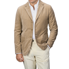 A person wearing an Aspesi Light Beige Cotton Velvet Isaac Blazer over a white shirt with beige pants.