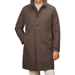 A person wearing a knee-length Marrone Brown Micro Nylon Thermore coat from Aspesi, with buttons and standing with one hand in the pocket.