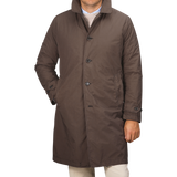 A person wearing a knee-length Marrone Brown Micro Nylon Thermore coat from Aspesi, with buttons and standing with one hand in the pocket.