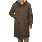 A person wearing an Aspesi Military Green Cotton Nylon Thermore Rams Parka with a hood and four buttons stands against a plain background.