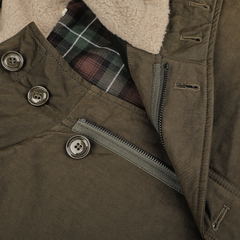 Close-up of the Aspesi Military Green Cotton Nylon Thermore Rams Parka, showcasing visible buttons, zippers, and a plaid inner lining. The jacket features Thermore padding for added warmth.