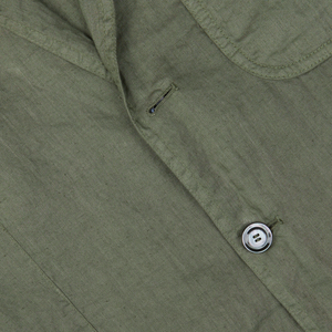 Close-up of a pure linen Aspesi Moss Green Washed Linen Samuraki Jacket fabric with a button and a small tear near the buttonhole.