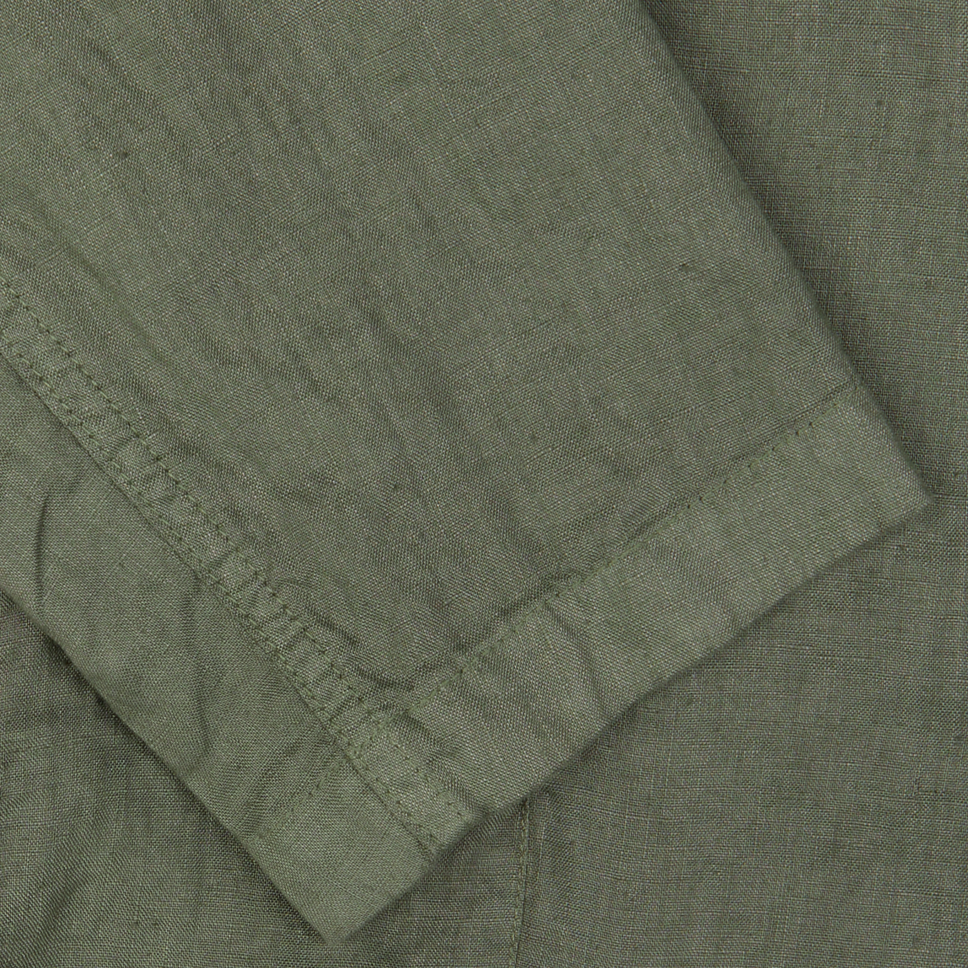 Close-up of green textured fabric with visible stitch detailing on the hem of an Aspesi Moss Green Washed Linen Samuraki Jacket.