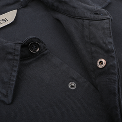 A close-up of a regular fit, navy blue field shirt from Aspesi, crafted from cotton twill, showcasing its visible buttons and snap fasteners as it lies flat.