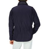 The man is wearing a Navy Blue Nylon Taffeta M65 field jacket by Aspesi with white pants.
