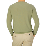 The back view of a man wearing an Aspesi Sage Green Cotton Piquet Crew Neck Sweater and khaki pants.