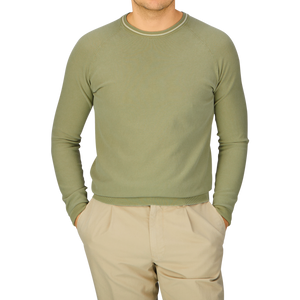A man wearing an Aspesi Sage Green Cotton Piquet Crew Neck Sweater and khaki pants.