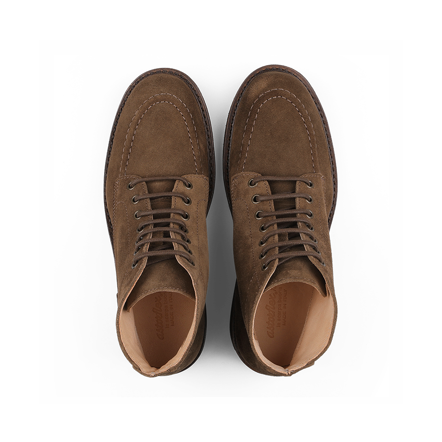 A pair of Dark Khaki Suede Leather Nuvoflex Boots by Astorflex with crepe rubber soles, viewed from the top on a black background.