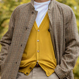 A person is wearing a houndstooth patterned coat over a Gran Sasso Mustard Yellow Extra Fine Merino Cardigan and a white shirt.