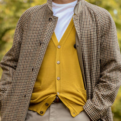 A person is wearing a houndstooth patterned coat over a Gran Sasso Mustard Yellow Extra Fine Merino Cardigan and a white shirt.