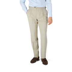 A man wearing a Baltzar Sartorial Beige Melange Wool Linen Pleated Trousers suit with tailored trousers and a blue shirt.