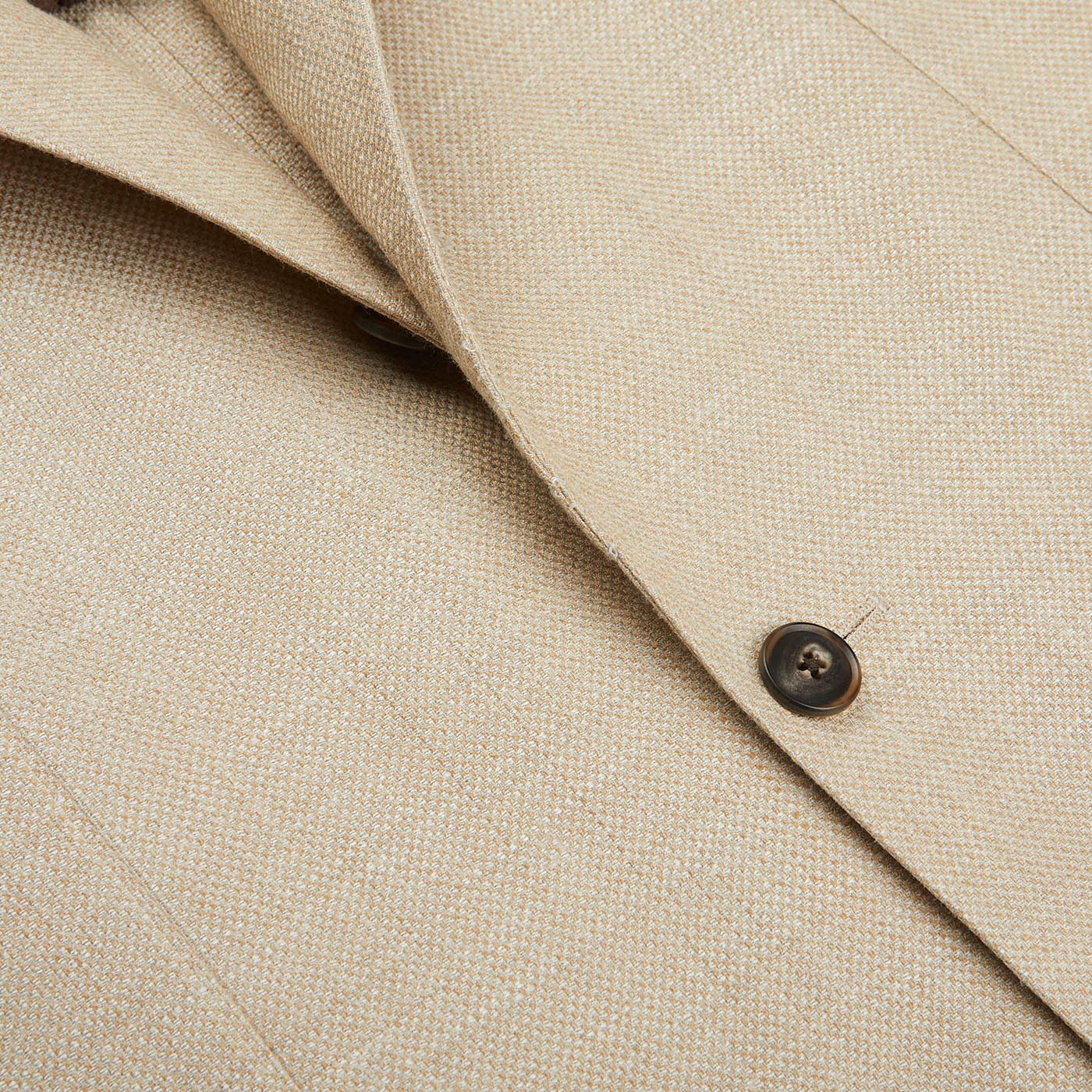 A close up of a Baltzar Sartorial Beige Melange Wool Silk Linen Blazer button.