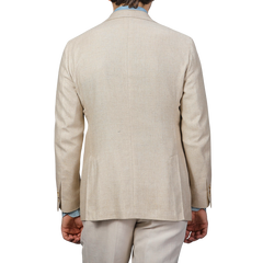 Rear view of a person in a Baltzar Sartorial Beige Wool Silk Summer Tweed Blazer and pants, with light blue shirt cuffs visible, against a plain background.