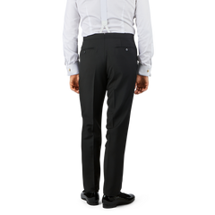 A person dressed in Baltzar Sartorial Black Wool Mohair Tuxedo Flat Front Trousers, a white shirt, and suspenders is shown from the back.